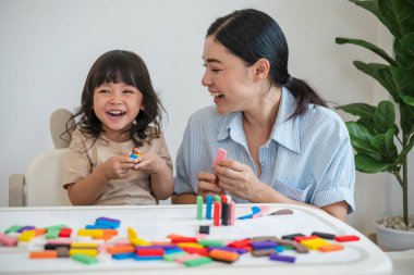Küçük kız ve annesi renkli tahta blok oyuncakları ya da domino oyunu oynuyorlar.