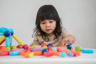 Küçük kız evde renkli manyetik inşaat oyuncağı oynuyor.