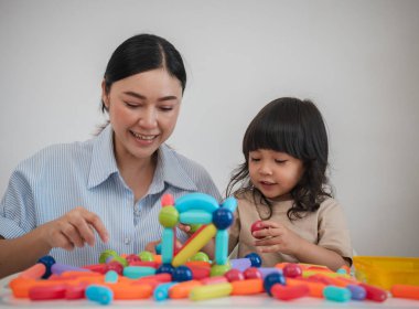 Küçük kız ve annesi evde renkli manyetik inşaat oyuncağı oynuyorlar.
