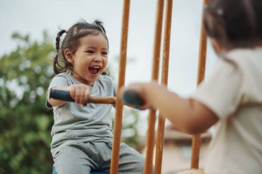 Neşeli küçük kız dışarıda Freind 'le çifte salıncakta oynuyor.