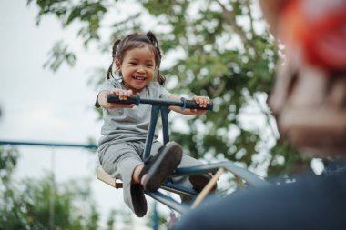 Küçük kız dışarıda tahterevallicilik oynuyor.