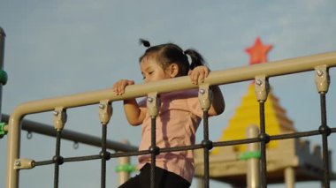 Parktaki çocuk parkında tırmanma halatlarıyla oynayan mutlu bir kız.