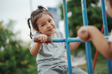 Neşeli küçük kız dışarıda Freind 'le çifte salıncakta oynuyor.