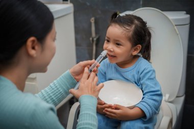 Anne, şırınga ve salinle küçük mutlu kız için burun yıkama yapıyor. Bebek burnunu temizliyorum.
