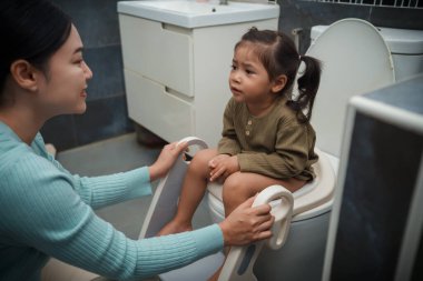 Annem küçük kızın tuvaleti kullanmasına yardım ediyor. Tuvalet eğitimi ve banyoda öğrenme.