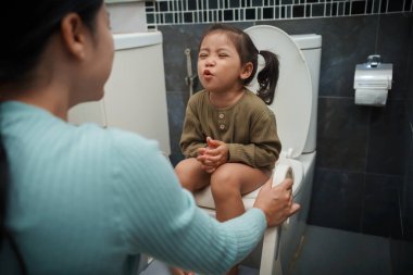 Annem küçük kızın tuvaleti kullanmasına yardım ediyor. Tuvalet eğitimi ve banyoda öğrenme.