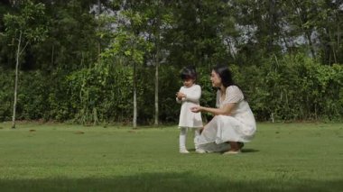Anne ve küçük kız parkta çim tarlasında dinleniyorlar.