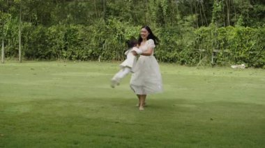 Anne ve küçük kız parkta çim tarlasında oynuyorlar.