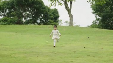 Yeşil çim tarlasında koşan beyaz elbiseli mutlu kız