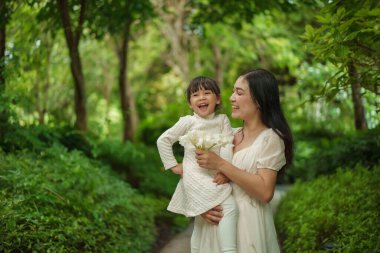 Mutlu anne kucağında ve bahçede küçük bir kızla konuşuyor.