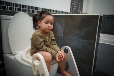 Küçük kız evdeki tuvalette oturuyor. Lazımlık eğitimi ve öğrenme