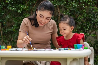 Mutlu anne ve bebek arka bahçedeki bir gazetede suluboya resim yapıyorlar.. 