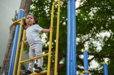 Parktaki çocuk parkında oynayan ve tırmanan mutlu kız.