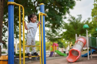 Parktaki çocuk parkında oynayan ve tırmanan mutlu kız.
