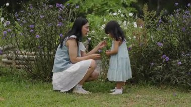 Mutlu anne ve küçük kız bahçede Ruellia tüberosa çiçeğiyle