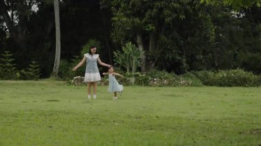 Mutlu anne ve yeni yürümeye başlayan kız çimen tarlasında birlikte dans edip oynuyorlar.