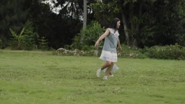 Anne ve küçük kız parkta çim tarlasında koşuşturmaca oynuyorlar.