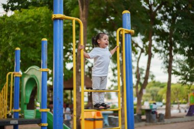 Parktaki çocuk parkında oynayan ve tırmanan mutlu kız.