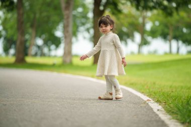 Mutlu küçük kız parkta bir patikada duruyor.