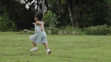 Yeşil çim tarlasında koşan, yeni yürümeye başlayan mutlu kız.