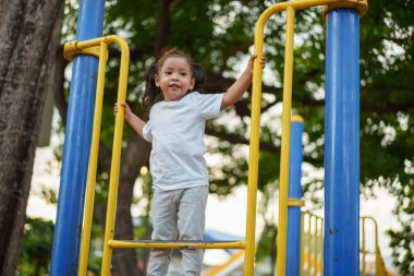 Parktaki çocuk parkında oynayan ve tırmanan mutlu kız.