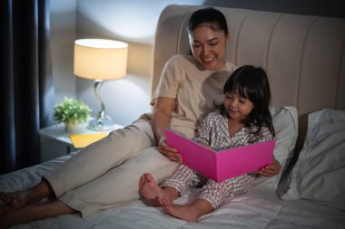 Anne, kitaptaki küçük kız için geceleri yatakta masal okurdu.