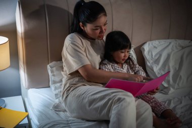 Anne, kitaptaki küçük kız için geceleri yatakta masal okurdu.