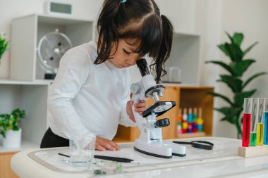 toddler girl scientist looking through a microscope. learning science