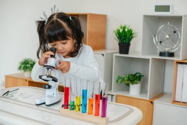 toddler girl scientist looking through a microscope. learning science