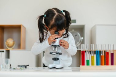 toddler girl scientist looking through a microscope. learning science