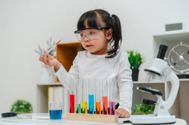 toddler girl scientist study using pipette dropping liquid with test tube and beaker. learning science