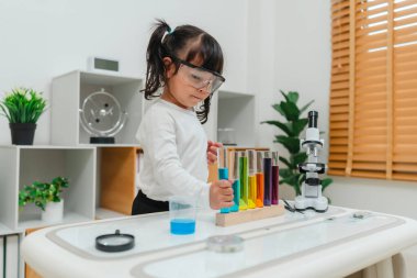 happy toddler girl scientist learning science with test tube and a beaker