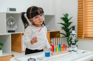 toddler girl scientist study using pipette dropping liquid with test tube and beaker. learning science