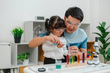 father and toddler girl scientist making chemical test with test tube. learning science at home
