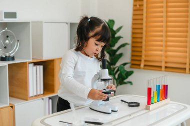 toddler girl scientist placing microscope slides with specimen. learning science at home