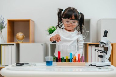 toddler girl scientist study using pipette dropping liquid with test tube and beaker. learning science