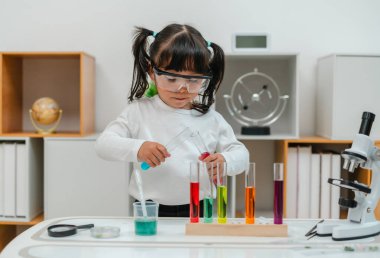 toddler girl scientist making chemical test with test tube and beaker. learning science at home