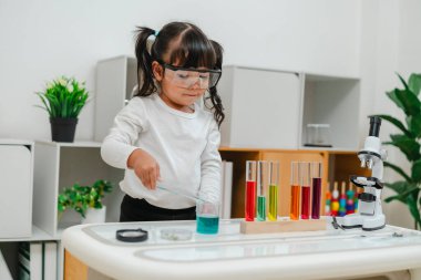 toddler girl scientist making chemical test with test tube and beaker. learning science at home