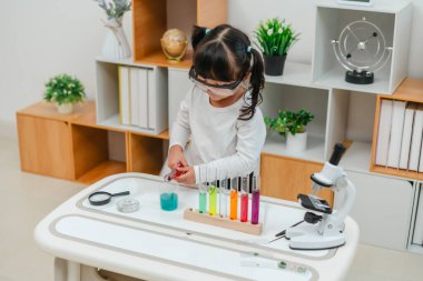 toddler girl scientist making chemical test with test tube and beaker. learning science at home