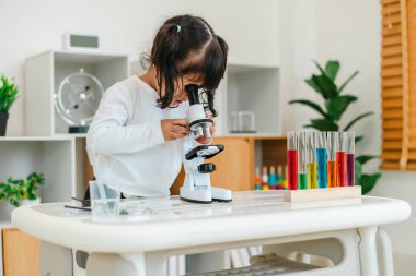 toddler girl scientist looking through a microscope. learning science