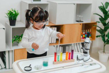 toddler girl scientist study using pipette dropping liquid with test tube and beaker. learning science