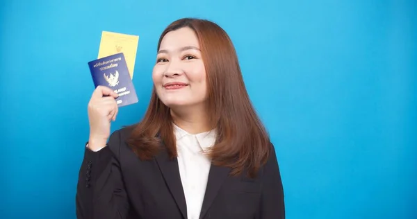 Asian businesswoman happy in suit and hand holding passport and vaccination card isolated on blue background