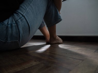 Kapalı alanda derin düşüncelere dalan kişinin ayaklarını ve bacaklarını ayarlayan minimalist çevresel zemin seviyesi öz-yansıma kavramı