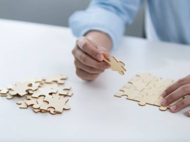 Ahşap bir yapboz ev çalışma alanı etkinliği oluşturuluyor. Kapalı alanda yaratıcı etkinlik, yakın plan görüş farkındalığı ve odaklanma sağlanıyor.