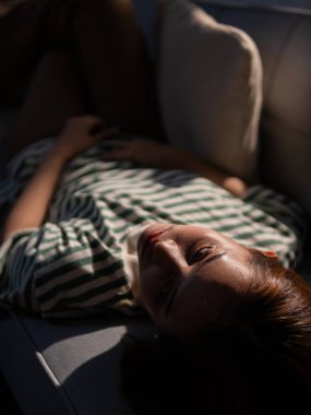 Rahatlatıcı anlar, kadın kanepenin üzerinde yaşam tarzını ayarlıyor, yumuşak ışıklandırma, samimi bir bakış açısı.