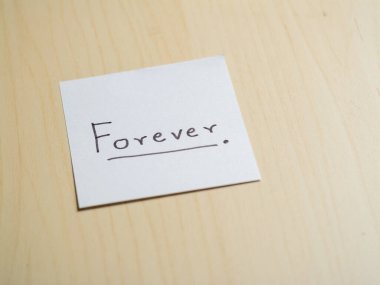 Minimalist bir ofis ortamında ilham verici bir el yazısı 'sonsuza kadar' notu