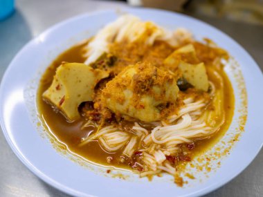 Canlı bir körili şehriye yemeği yerel bir lokantada servis edilir. Kalabalık bir şehir ortamında lezzet ve dokular sergilenir..