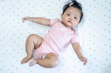 Çekici, yeni doğmuş Asyalı bir bebek masumiyet ve neşe saçan rahat bir ev ortamında neşeyle yatıyor..