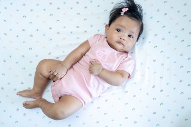 Pembe giyinmiş, sevimli, yeni doğmuş Asyalı bir bebek. Kapalı bir ortamda rahatlıyor..