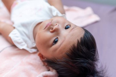 Yeni doğmuş Asyalı bir bebeğin büyüleyici bir portresi masum merakını sıcak bir iç mekanda gösteriyor..